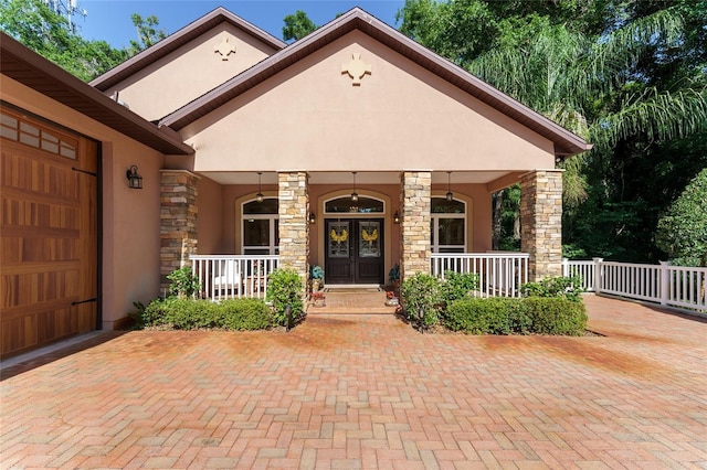 552 NW 136th St, Newberry, FL 32669 - view of exterior entry with stucco siding, a porch, stone siding, and an attached garage