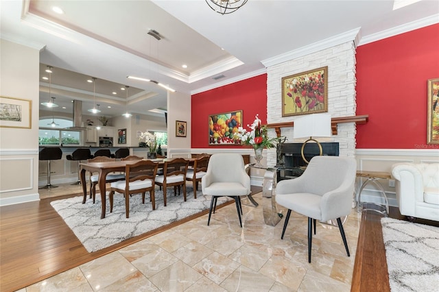 552 NW 136th St, Newberry, FL 32669 - dining space featuring a raised ceiling, ornamental molding, a decorative wall, a fireplace, and a wainscoted wall