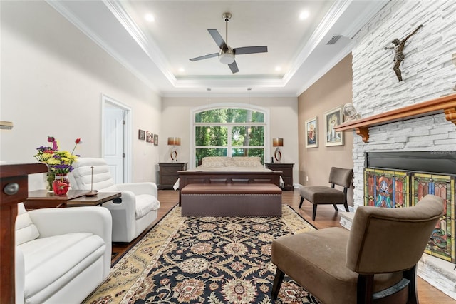 552 NW 136th St, Newberry, FL 32669 - living room featuring wood finished floors, a ceiling fan, a stone fireplace, a raised ceiling, and crown molding