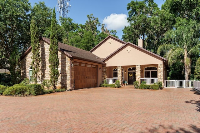 552 NW 136th St, Newberry, FL 32669 - view of front of home featuring covered porch, an attached garage, stone siding, stucco siding, and decorative driveway