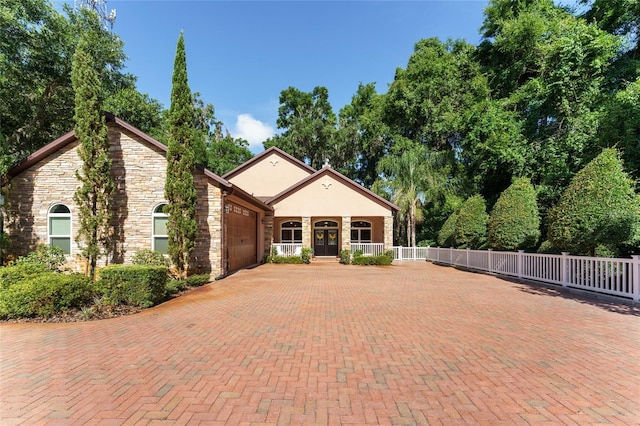 552 NW 136th St, Newberry, FL 32669 - view of front of property featuring a garage, french doors, decorative driveway, and stone siding