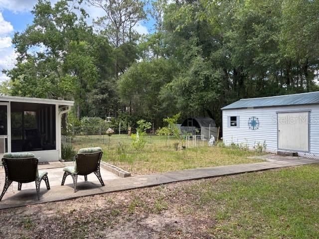8411 N Pine Needle Ter, Crystal River, FL 34428 - view of yard with a sunroom, view of scattered trees, an outbuilding, and a patio area