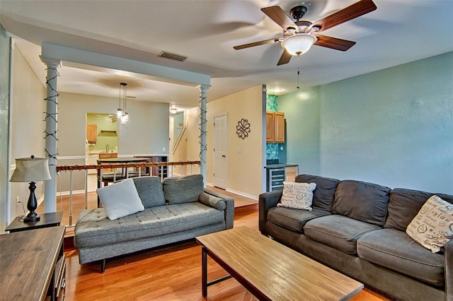 832 NW 42nd Ter, Gainesville, FL 32605 - living area with ceiling fan, beverage cooler, light wood-style flooring, and decorative columns