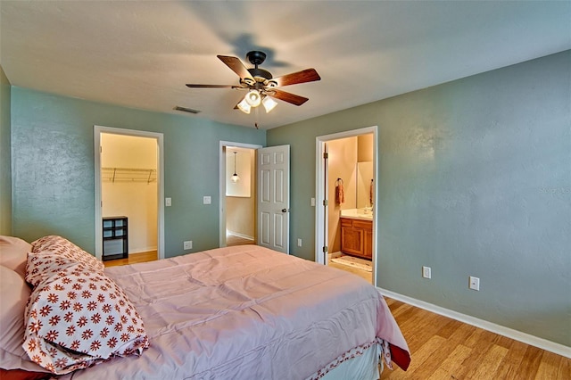 832 NW 42nd Ter, Gainesville, FL 32605 - bedroom with light wood-style flooring, a walk in closet, ensuite bathroom, and a ceiling fan