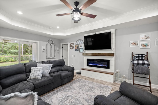 15591 NE 14th Pl, Williston, FL 32696 - living area featuring ornamental molding, a ceiling fan, a glass covered fireplace, wood finished floors, and a tray ceiling