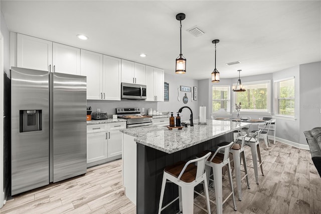 15591 NE 14th Pl, Williston, FL 32696 - kitchen with stainless steel appliances, white cabinetry, light wood finished floors, light stone countertops, and recessed lighting