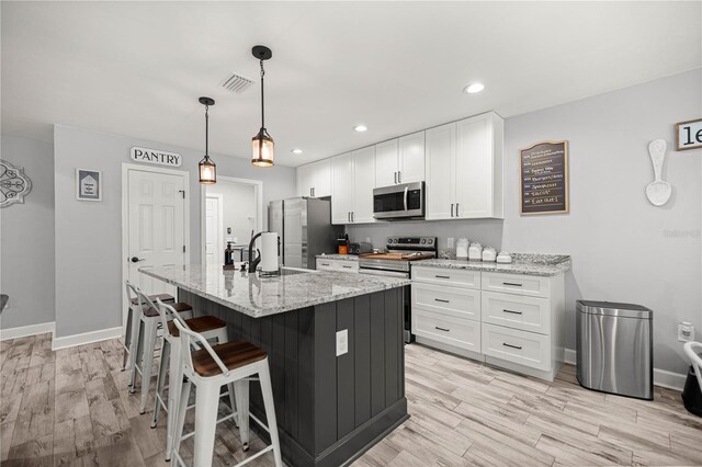 15591 NE 14th Pl, Williston, FL 32696 - kitchen with appliances with stainless steel finishes, white cabinetry, a breakfast bar area, light stone countertops, and recessed lighting