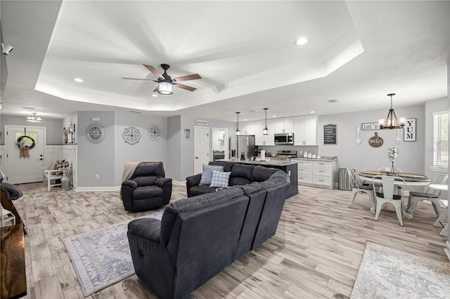 15591 NE 14th Pl, Williston, FL 32696 - living room featuring a raised ceiling, light wood-style flooring, crown molding, ceiling fan, and a chandelier
