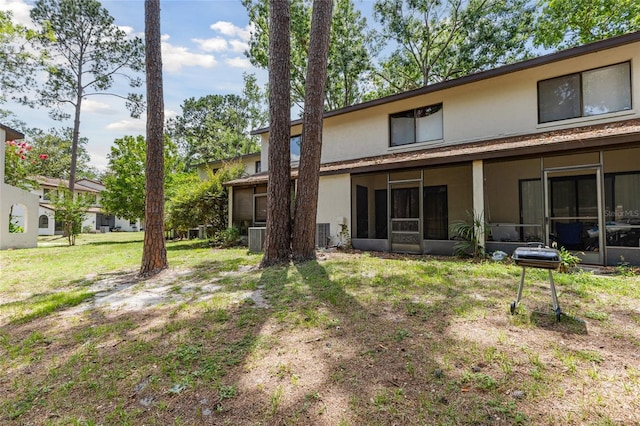 2635 SW 35th Pl Unit 304, Gainesville, FL 32608 - rear view of house with a sunroom, stucco siding, and a lawn