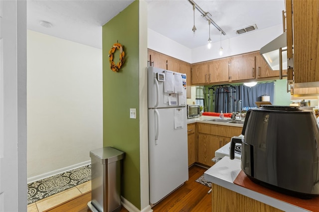 2635 SW 35th Pl Unit 304, Gainesville, FL 32608 - kitchen with freestanding refrigerator, stainless steel microwave, brown cabinets, and dark wood-style flooring