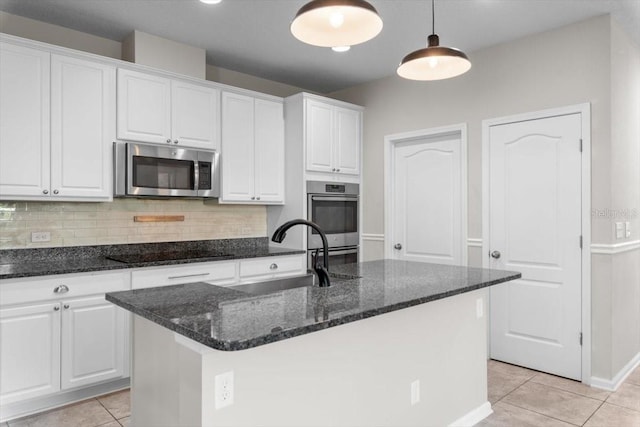 1011 Wetland Ridge Cir, Middleburg, FL 32068 - kitchen featuring appliances with stainless steel finishes, white cabinets, light tile patterned floors, tasteful backsplash, and a kitchen island with sink