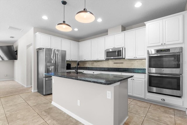 1011 Wetland Ridge Cir, Middleburg, FL 32068 - kitchen featuring appliances with stainless steel finishes, white cabinetry, light tile patterned floors, hanging light fixtures, and decorative backsplash