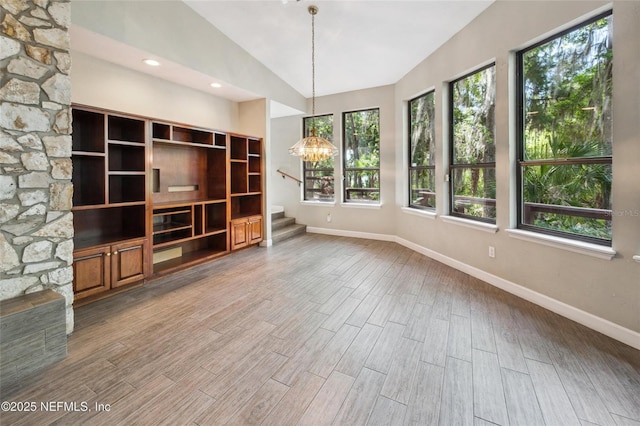 110 Cypress St, Hawthorne, FL 32640 - unfurnished living room with plenty of natural light, stairs, lofted ceiling, wood finished floors, and a chandelier