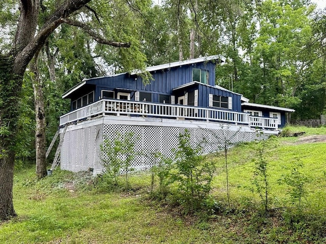 9947 SW 37th St, Lake Butler, FL 32054 - back of house featuring board and batten siding, a wooden deck, and a wooded view