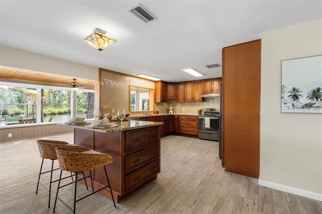 900 NW Snug Harbor Rd, Crystal River, FL 34428 - kitchen with stainless steel electric range, a kitchen breakfast bar, and light wood-style flooring