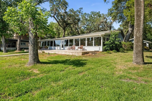 900 NW Snug Harbor Rd, Crystal River, FL 34428 - rear view of house with a patio, a lawn, and a sunroom
