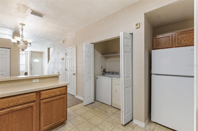 3901 SW 20th Ave Unit 806, Gainesville, FL 32607 - kitchen featuring freestanding refrigerator, washer and dryer, light countertops, a chandelier, and hanging light fixtures