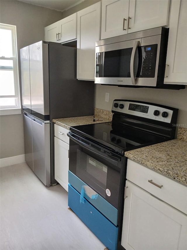 6519 W Newberry Rd Unit 404, Gainesville, FL 32605 - kitchen featuring stainless steel microwave, range with electric stovetop, white cabinets, and light stone countertops