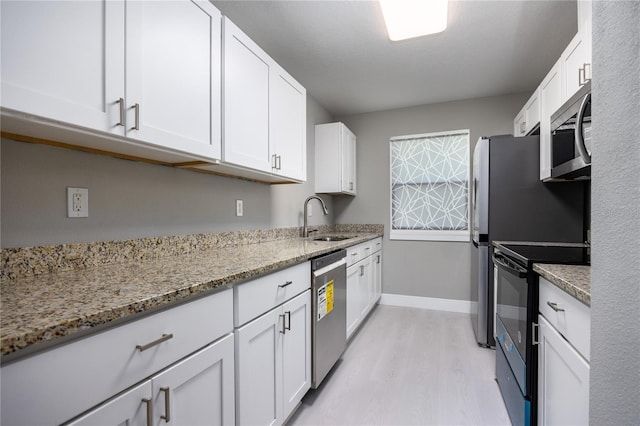 6519 W Newberry Rd Unit 404, Gainesville, FL 32605 - kitchen with stainless steel appliances, light wood-type flooring, white cabinetry, and light stone countertops