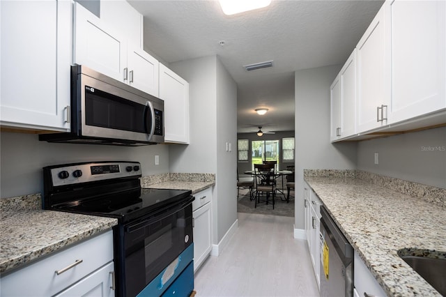 6519 W Newberry Rd Unit 404, Gainesville, FL 32605 - kitchen with stainless steel appliances, a ceiling fan, light wood finished floors, white cabinets, and light stone countertops