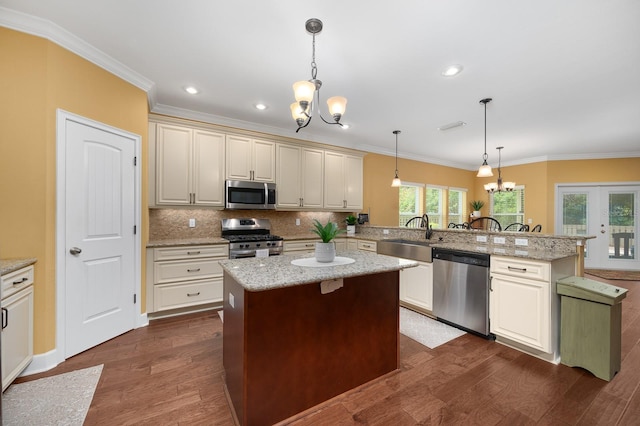 7827 SW 79th Dr, Gainesville, FL 32608 - kitchen with appliances with stainless steel finishes, a chandelier, a peninsula, tasteful backsplash, and ornamental molding