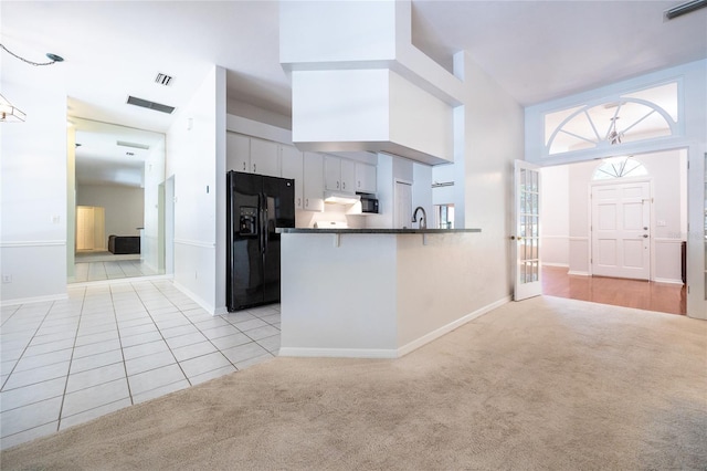 2013 SW 76th Ter, Gainesville, FL 32607 - kitchen with black refrigerator with ice dispenser, dark countertops, a peninsula, light carpet, and light tile patterned floors
