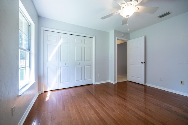 2013 SW 76th Ter, Gainesville, FL 32607 - unfurnished bedroom featuring wood finished floors, multiple windows, a closet, and a ceiling fan