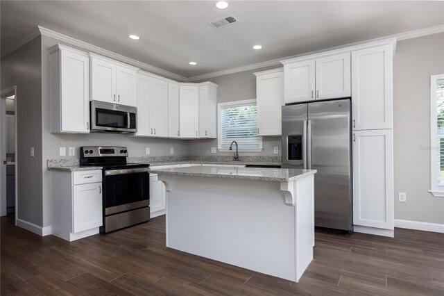 16011 S County Road 325, Hawthorne, FL 32640 - kitchen with stainless steel appliances, crown molding, a center island, white cabinetry, and light stone countertops