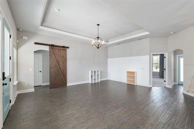 2556 SW 118th Ter, Gainesville, FL 32608 - unfurnished living room with arched walkways, a raised ceiling, a barn door, and dark wood-style flooring