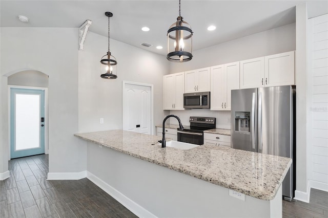 2556 SW 118th Ter, Gainesville, FL 32608 - kitchen featuring appliances with stainless steel finishes, arched walkways, a peninsula, white cabinetry, and lofted ceiling