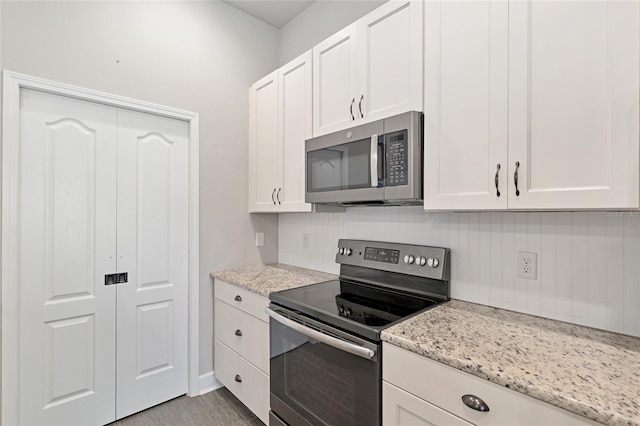 2556 SW 118th Ter, Gainesville, FL 32608 - kitchen featuring stainless steel appliances, white cabinets, light stone countertops, and wood finished floors