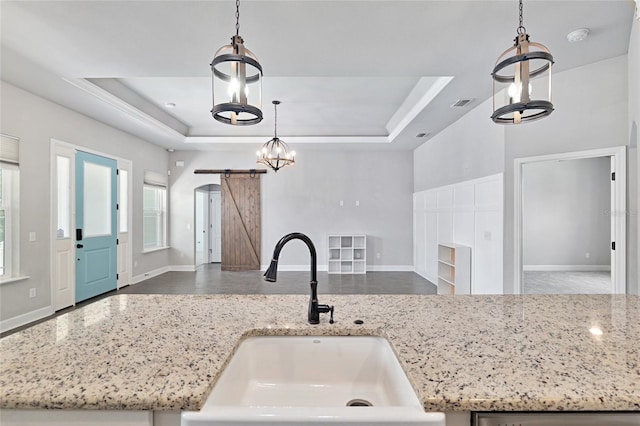 2556 SW 118th Ter, Gainesville, FL 32608 - kitchen with a chandelier, open floor plan, a tray ceiling, pendant lighting, and light stone countertops