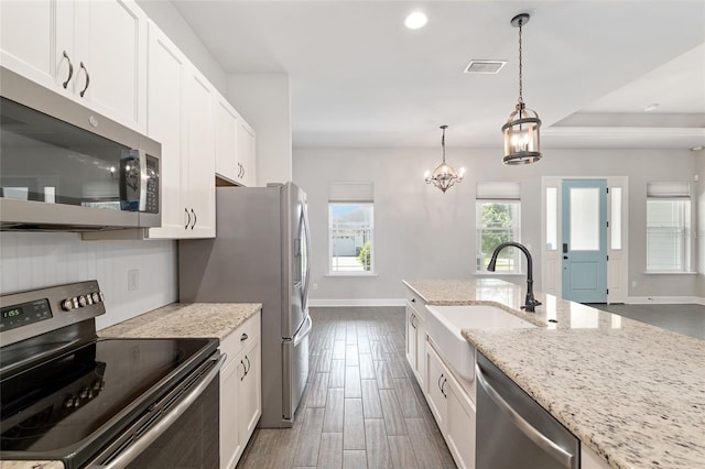 2556 SW 118th Ter, Gainesville, FL 32608 - kitchen with stainless steel appliances, white cabinetry, light stone counters, a chandelier, and recessed lighting