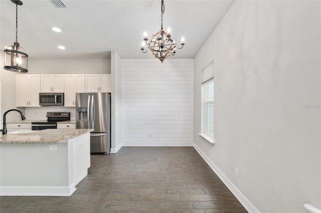2556 SW 118th Ter, Gainesville, FL 32608 - kitchen featuring stainless steel appliances, a chandelier, white cabinets, light stone counters, and decorative light fixtures