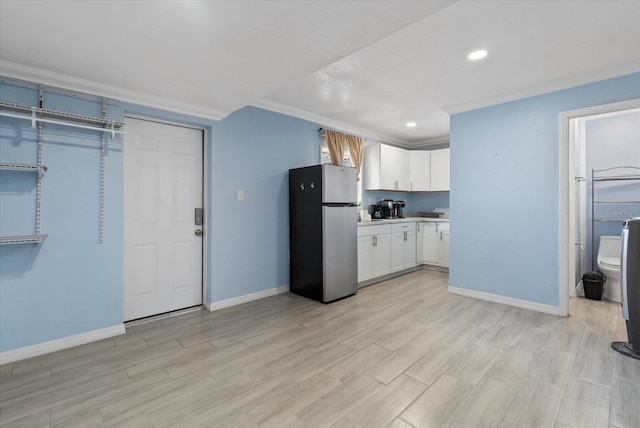 4444 5th Ave S, Saint Petersburg, FL 33711 - kitchen with freestanding refrigerator, white cabinetry, light wood-type flooring, light countertops, and crown molding