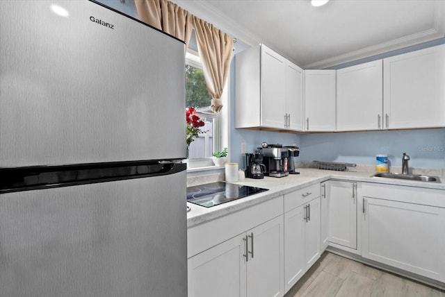 4444 5th Ave S, Saint Petersburg, FL 33711 - kitchen with freestanding refrigerator, black electric cooktop, light countertops, white cabinetry, and ornamental molding