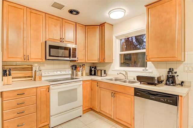 1318 NW 7th Rd, Gainesville, FL 32603 - kitchen featuring appliances with stainless steel finishes, light countertops, backsplash, light tile patterned flooring, and light brown cabinetry