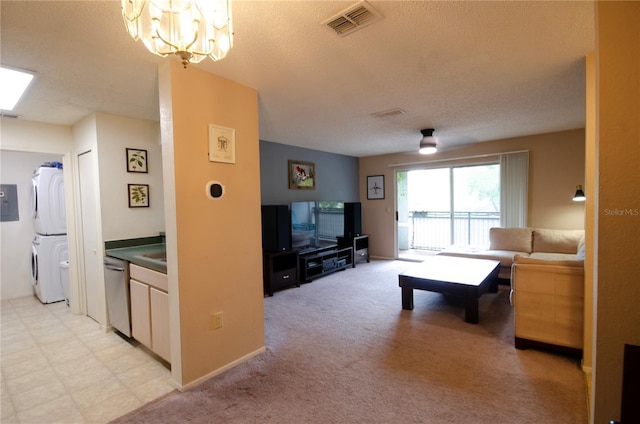 3705 SW 27th St Unit 223, Gainesville, FL 32608 - living room featuring stacked washer and clothes dryer, a textured ceiling, a chandelier, and light colored carpet