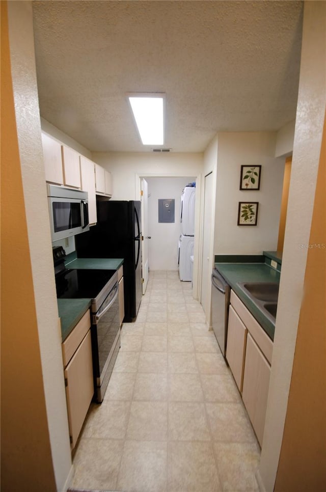 3705 SW 27th St Unit 223, Gainesville, FL 32608 - kitchen featuring appliances with stainless steel finishes, dark countertops, a textured ceiling, electric panel, and stacked washing machine and dryer