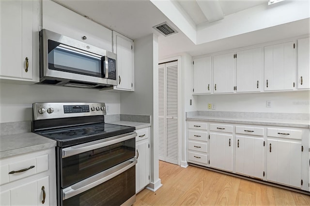 1745 NW 42nd Ave, Gainesville, FL 32605 - kitchen with appliances with stainless steel finishes, light wood-style floors, light countertops, and white cabinets