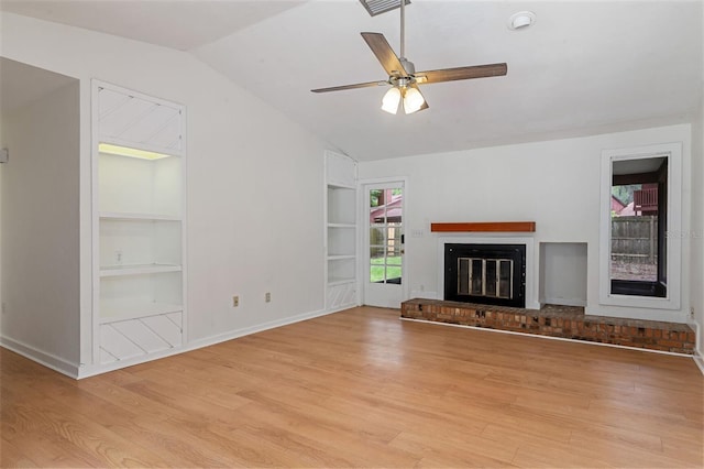 1745 NW 42nd Ave, Gainesville, FL 32605 - unfurnished living room featuring built in features, vaulted ceiling, light wood-style flooring, ceiling fan, and a fireplace