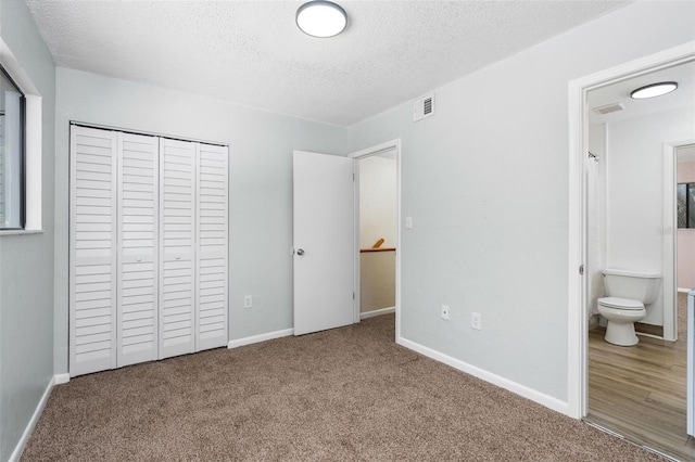 4325 NW 41st Pl Unit 6, Gainesville, FL 32606 - unfurnished bedroom featuring a textured ceiling, carpet, a closet, and ensuite bath