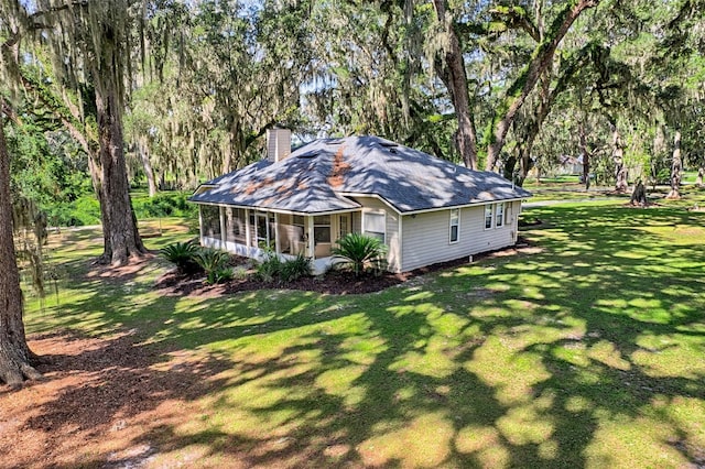 6505 SW 135th Pl, Archer, FL 32618 - view of home's exterior with a chimney, a sunroom, a lawn, a shingled roof, and view of scattered trees