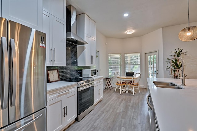 6505 SW 135th Pl, Archer, FL 32618 - kitchen featuring stainless steel appliances, wall chimney exhaust hood, light countertops, light wood-style floors, and backsplash