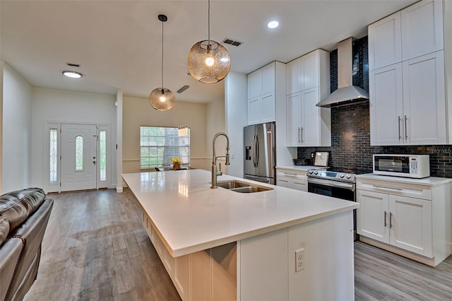 6505 SW 135th Pl, Archer, FL 32618 - kitchen with wall chimney range hood, white microwave, stainless steel fridge with ice dispenser, light wood-style flooring, and a kitchen island with sink