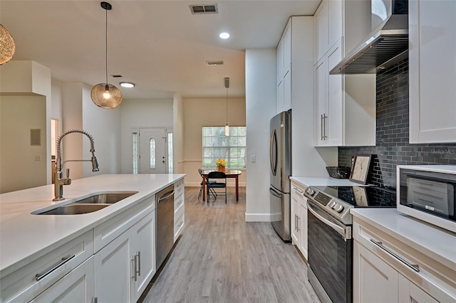 6505 SW 135th Pl, Archer, FL 32618 - kitchen with stainless steel appliances, backsplash, wall chimney range hood, light wood-style floors, and light countertops
