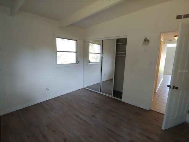 2904 NE 11th Ter, Gainesville, FL 32609 - unfurnished bedroom with beamed ceiling, dark wood finished floors, and a closet