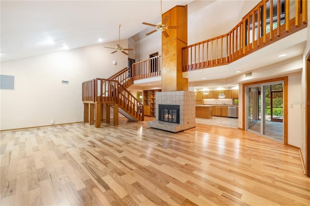 1225 NW 23rd Ter, Gainesville, FL 32605 - unfurnished living room featuring light wood-type flooring, ceiling fan, stairway, high vaulted ceiling, and a fireplace