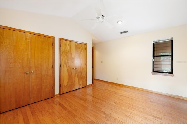 1225 NW 23rd Ter, Gainesville, FL 32605 - unfurnished bedroom with two closets, light wood-style floors, lofted ceiling, and a ceiling fan