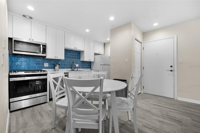 1700 SW 16th Ct Unit E9, Gainesville, FL 32608 - kitchen with appliances with stainless steel finishes, light wood-style flooring, light countertops, white cabinets, and recessed lighting